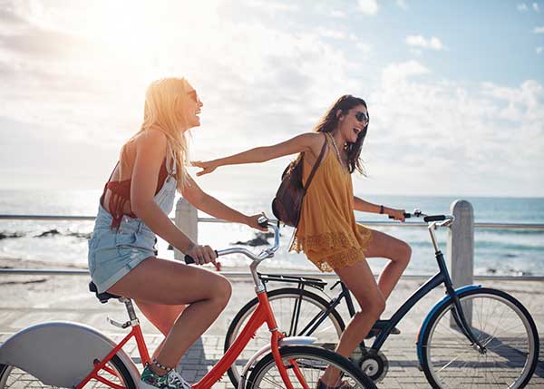 2 woman riding bikes on the strand by the beach